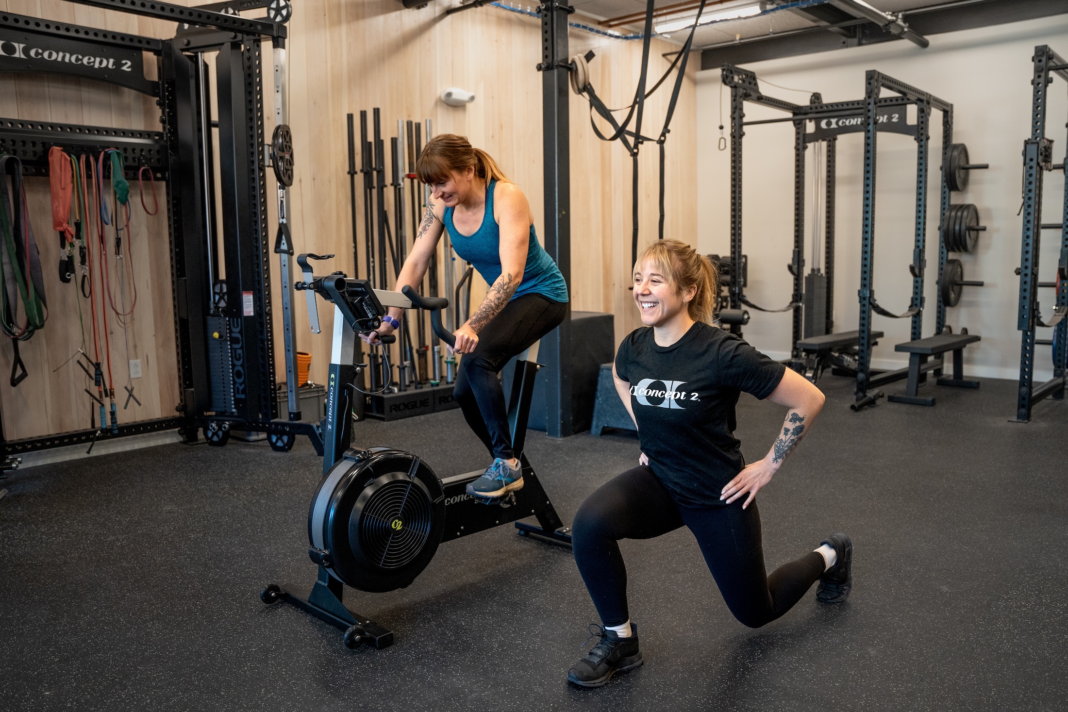 Woman on BikeErg while someone lunges beside her